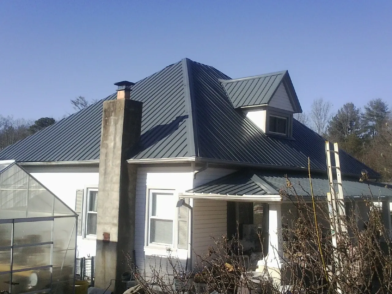 Dark blue standing seam metal roof on a white farmhouse with dormer — Slate & Tile Roof Repair by Roofing Brothers in Pevely