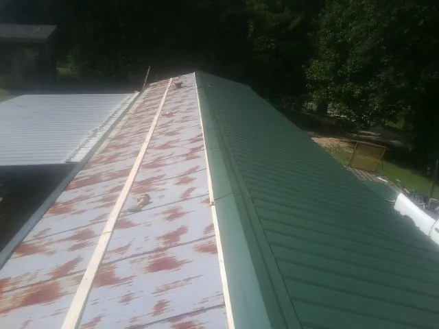 Old rusted panels beside newly installed green metal roofing — Wind Damage Roof Repair by Roofing Brothers in Pevely