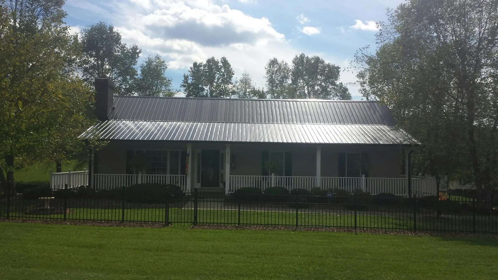 Gray metal roof on a brick ranch with a full width front porch — Gutter Guard Installation work by our crew in Pevely