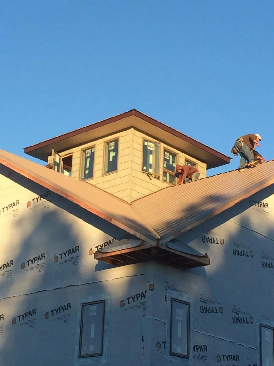 Roofers working around a rooftop cupola on a new metal roof at sunset — Roof Waterproofing in Pevely by Roofing Brothers